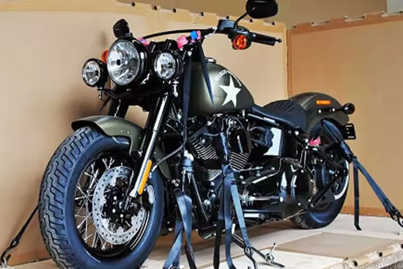 Military-style motorcycle secured on a wooden pallet, surrounded by cardboard, ready for shipment. Highlights shipping preparation for a valuable item.